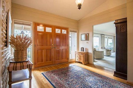 Do Persian Style Rugs Shed? Let’s Find Out! An inviting entryway features warm wooden double doors, a patterned rug, and a rustic console table, leading into a bright living area. Photo by Clay Elliot
