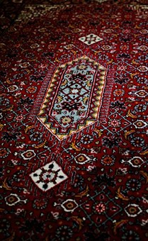 Persian Rugs vs Afghan Rugs: Unraveling the Artistry of Two Timeless Traditions A richly detailed red rug features a central medallion and intricate patterns in shades of blue, gold, and white. Photo by SAJAD FI