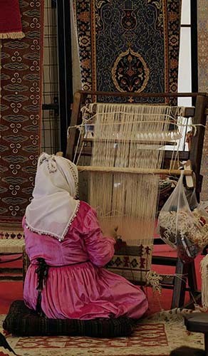 Do Persian Style Rugs Shed? Let’s Find Out! A weaver in traditional attire meticulously works on a loom, creating an intricate pattern on a rug. Photo by Sena Şenol