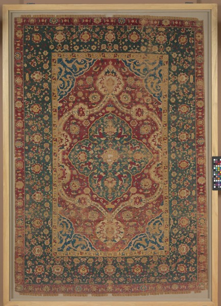 Kashan Persian Rugs A historical Kashan Persian rug with intricate floral medallions in red, blue, and ivory, displayed at the Metropolitan Museum of Art. Image courtesy of The Metropolitan Museum of Art.