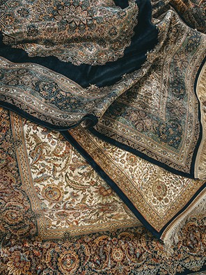 The Enduring Artistry of High End Rugs A stunning display of traditional rugs, featuring rich jewel tones, intricate floral motifs, and detailed borders. Each one a masterpiece of textile art. Photo by Paolo Bici